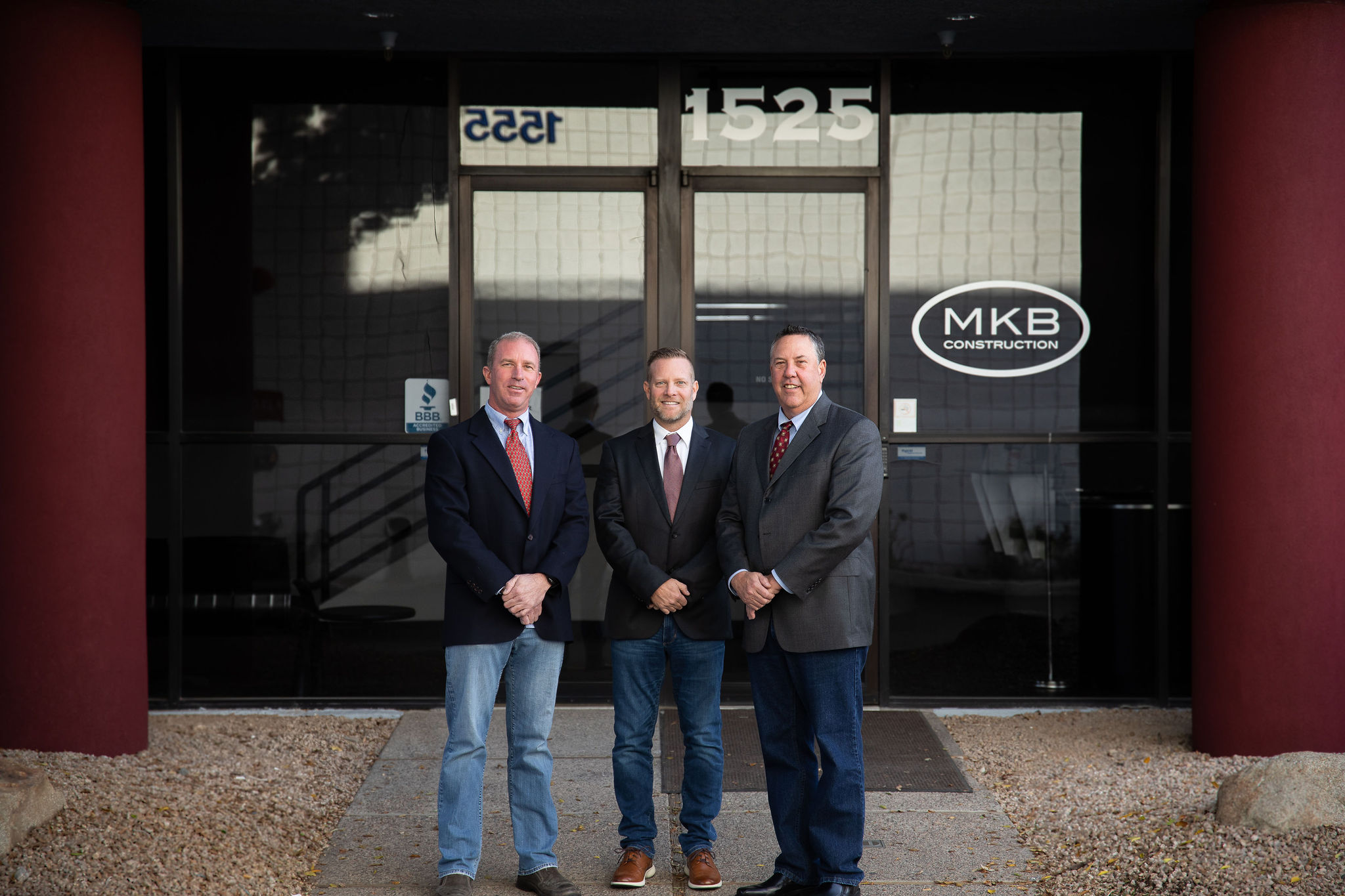 Three men from MKB Construction Inc. standing in front of a building, showcasing their quality services.