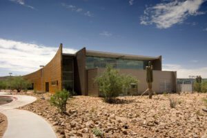 A building with rocks and cactus in the background, provided by MKB Construction Services.