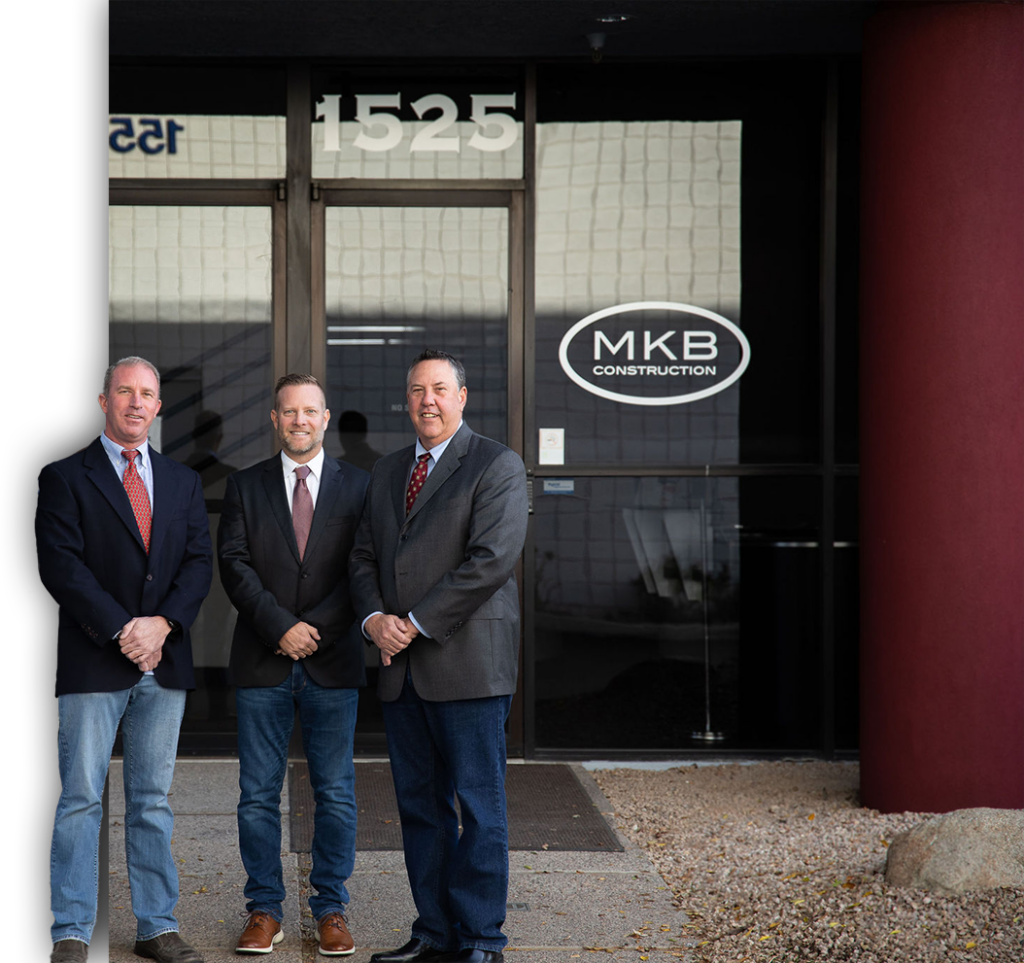 Three men from MKB Construction Inc. are standing in front of a building while showcasing their commitment to providing quality services.