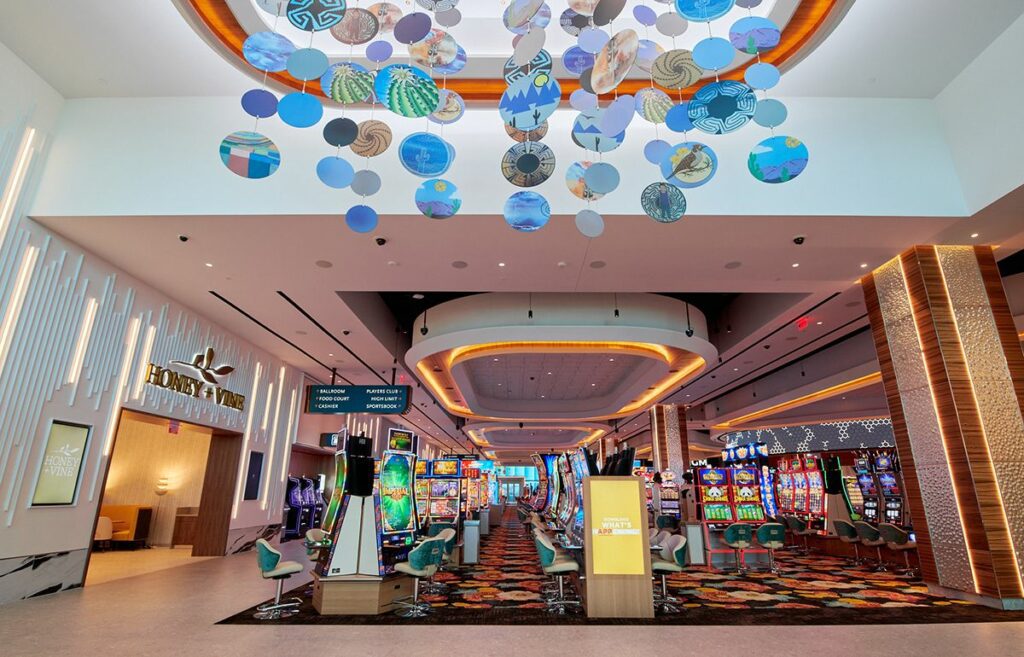 Interior of the Gila River Santan Mountain Casino, featuring slot machines, decorative overhead disks, bright lighting, and signage for "high limit slots.