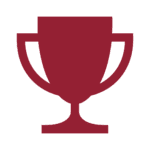A simple red trophy icon with a cup and handle design on a white background, provided by MKB Construction Services.
