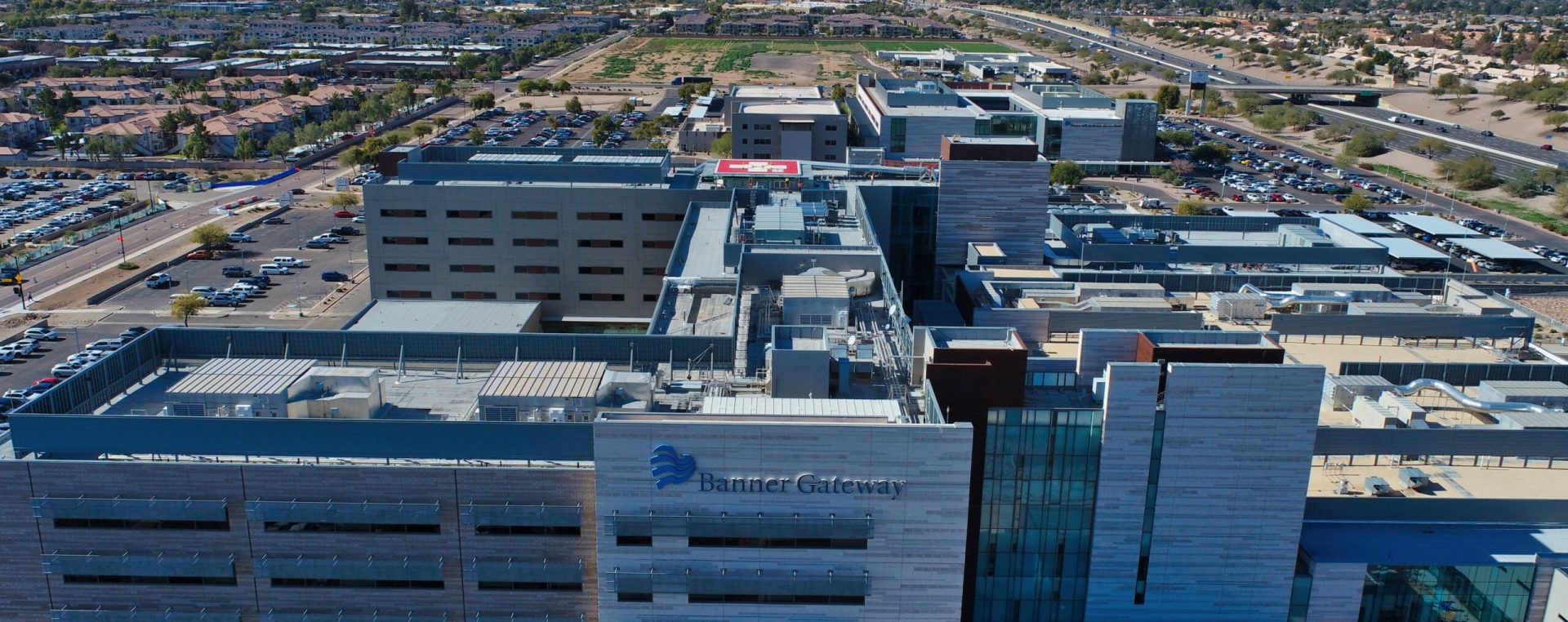 Aerial view of Banner MD Anderson Cancer Center with surrounding parking and landscaped areas in a sunny suburban setting.